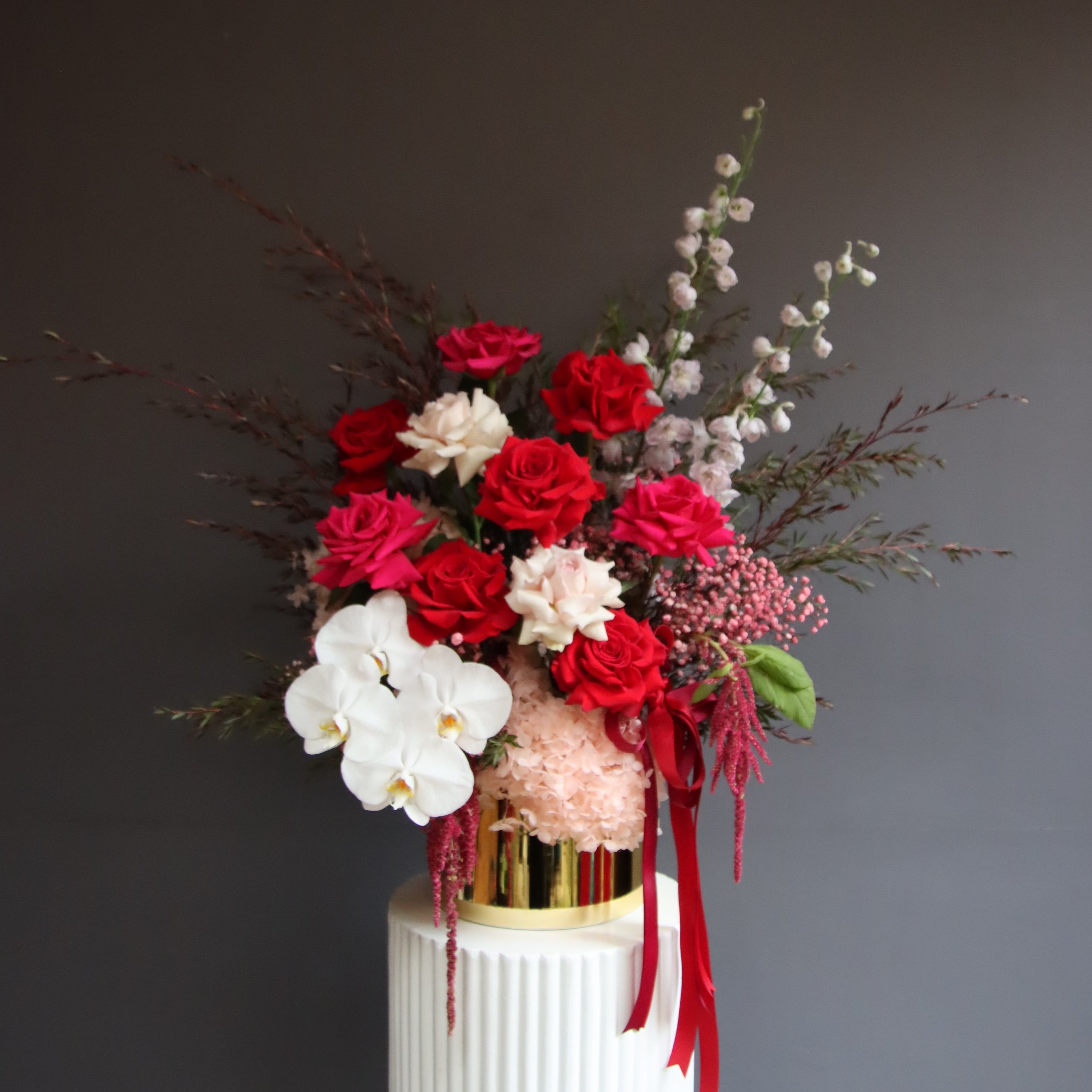 Grand reflexed rose and orchid arrangement in gold glass pot – Ruby by Ivy & Twig Florist