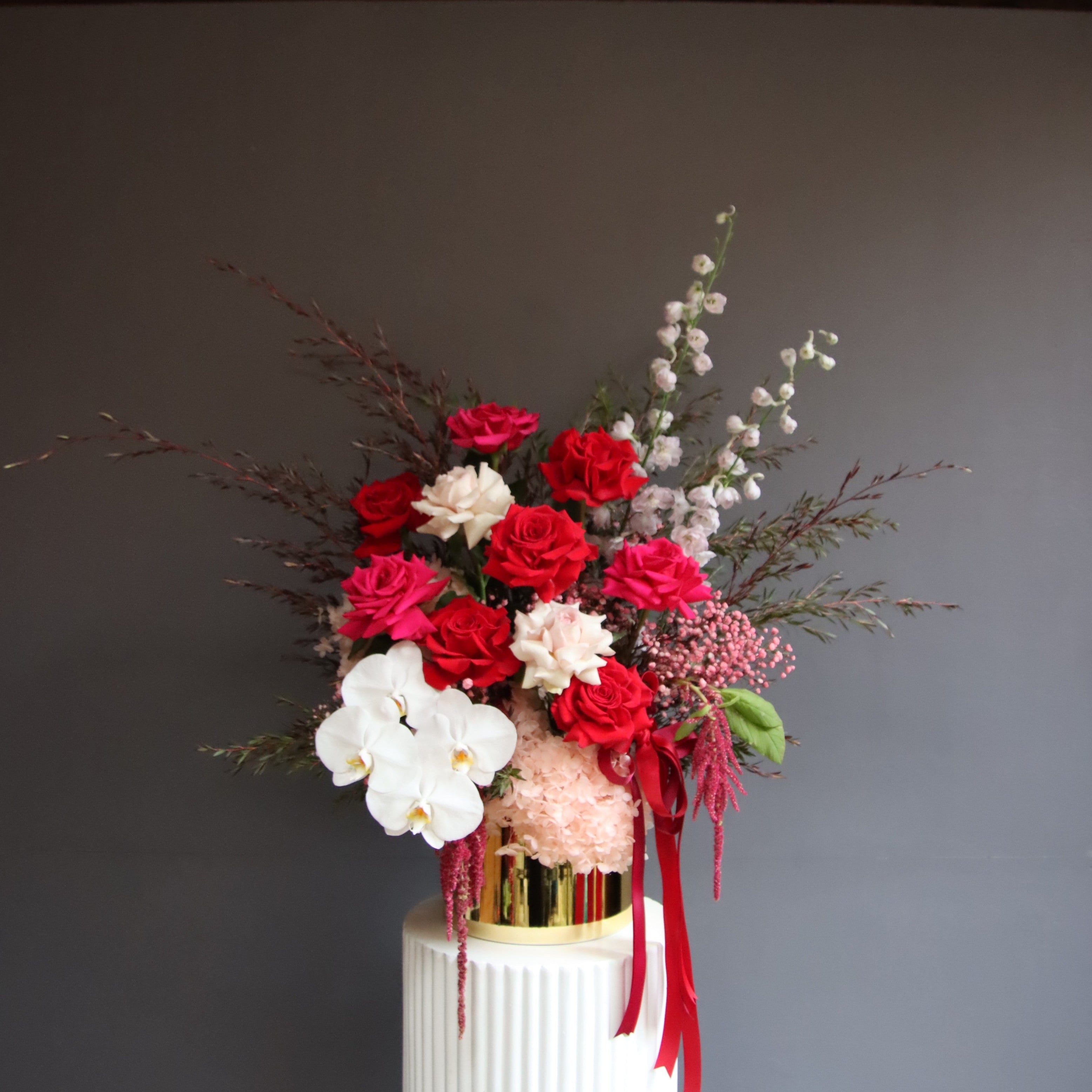 Grand reflexed rose and orchid arrangement in gold glass pot – Ruby by Ivy & Twig Florist