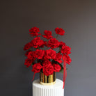 Red reflexed roses arranged in a gold glass pot